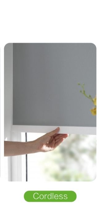 Hand lifting a cordless roller blind with no visible chain or cord.